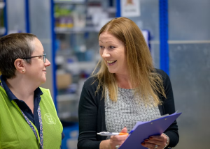 Woman talking and writing on a clipboard in a medical setting